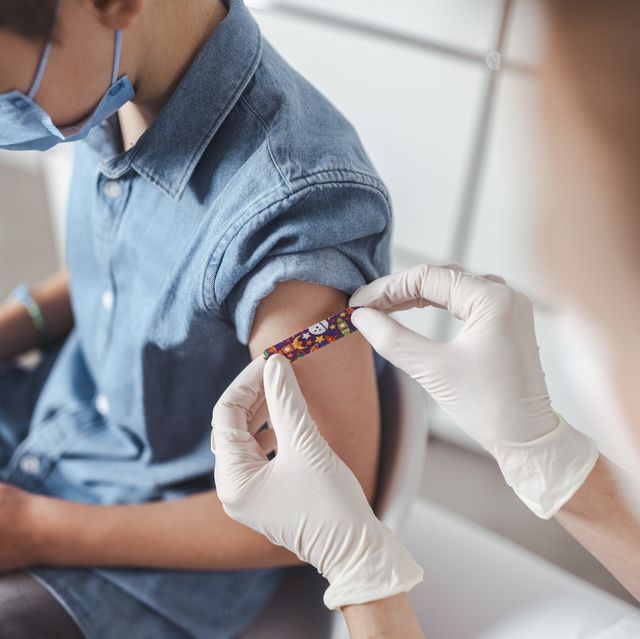 nurse putting adhesive bandage on boy's arm at vaccination center