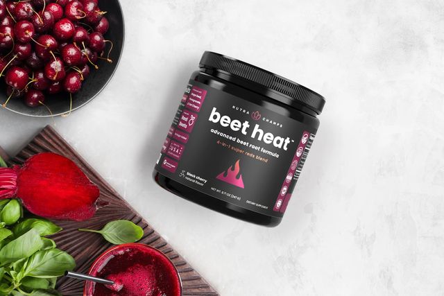 nutrachamps beet heat powder on a countertop with a smoothie, cherries, beets, and basil leaves