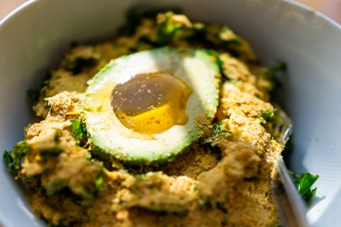 Macro vue rapprochée de la salade végétarienne végétalienne verte de chou frisé avec beaucoup de levure nutritionnelle et d'avocat à moitié rempli d'huile d'olive repas végétalien dans un bol