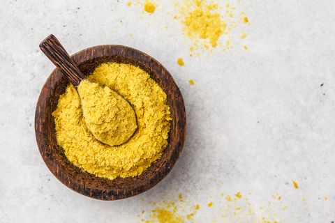 Nutritional yeast in a wooden bowl, copy space. Healthy vegan food concept.