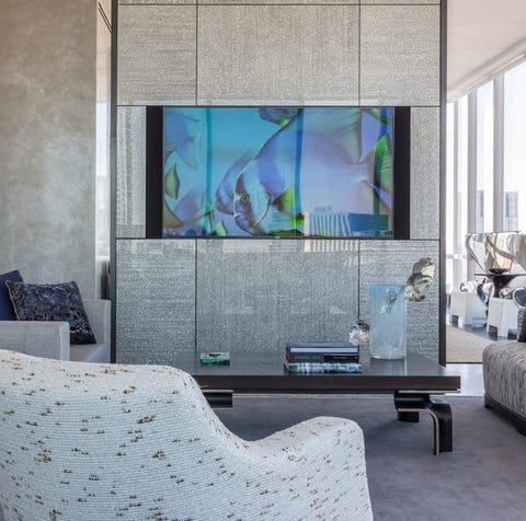 living room with wall separator with built in tv and a chair in the foreground