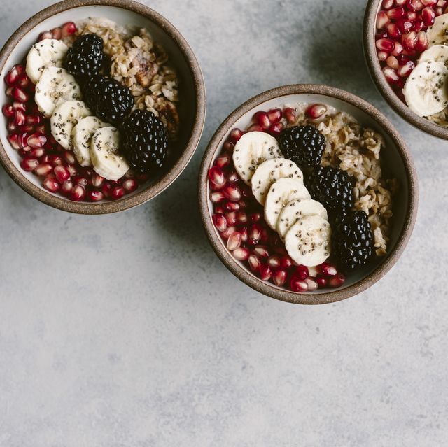 3 oatmeal bowls topped off with blackberry, banana, and pomegranate seeds are photographed from the top view.