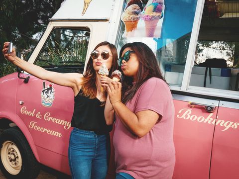 obese woman and her slim friend eating ice cream from ice cream truck