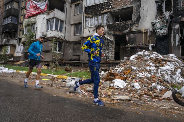 hardlopers in oekraïne lopen langs kapotte huizen