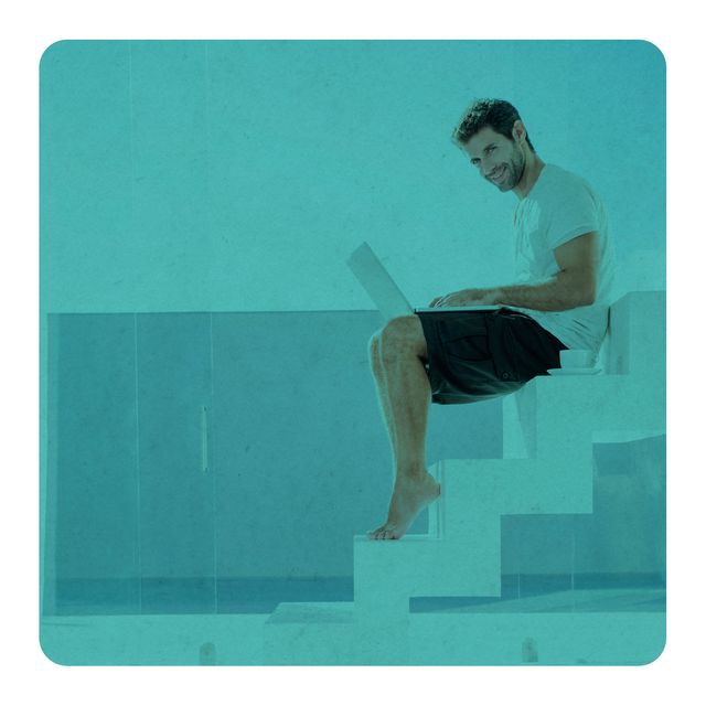 un hombre teclea en un ordenador portátil sentado en unas escaleras
