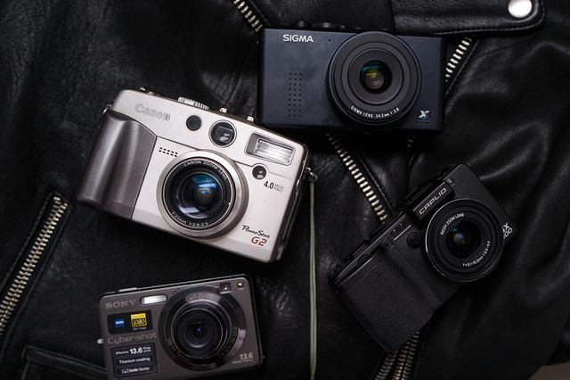 four cameras laying on a black leather jacket