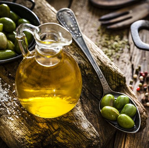 Olive oil bottle and green olives shot on rustic wooden table
