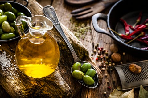 Olive oil bottle and green olives shot on rustic wooden table