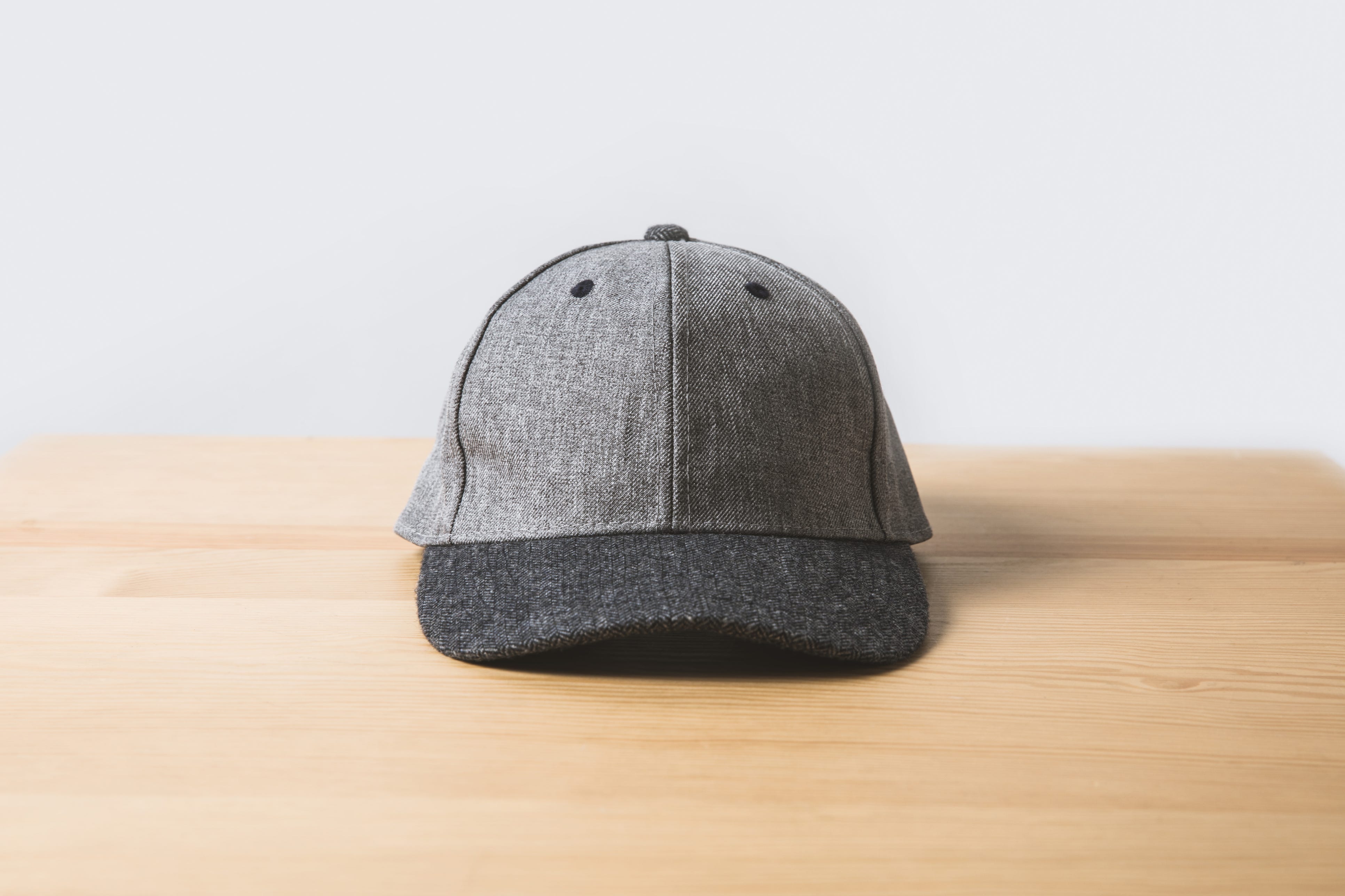 Una gorra gris sobre una mesa de madera sobre blanco