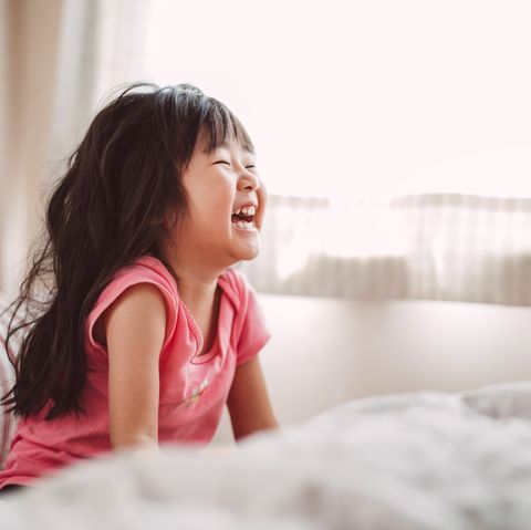 Little girl laughing joyfully in bed