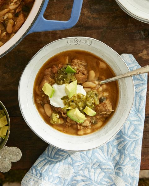 white turkey chili in a bowl topped with sour cream and diced avocados