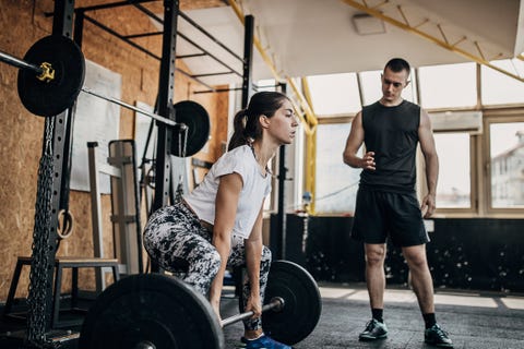 One young woman having weight training with fitness instructor one young woman having weight training with fitness instructor
