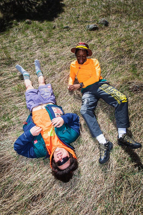 two men wearing the north face x online ceramics collaboration laying down on grassy field