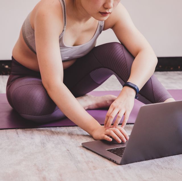 online personal training sessions review before and after results picture shows a woman sat on a yoga mat, looking at her laptop
