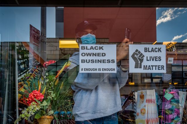 open storefront displaying a black owned business sign