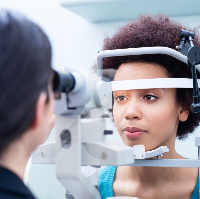 ophthalmologist examining woman wearing eye test equipment