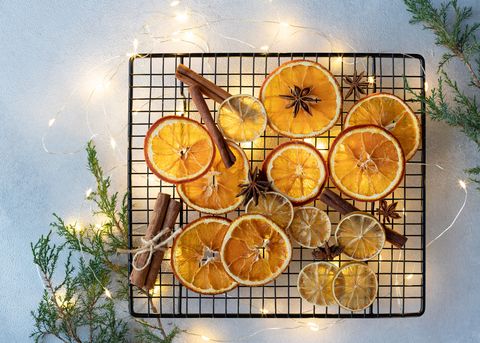 dried oranges, lemons, cinnamon sticks and anise stars on a background of christmas lights and fir branches ingredients for cooking or christmas decoration flat lay space for text