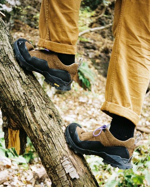 person wearing roa hiking shoe climbing up log