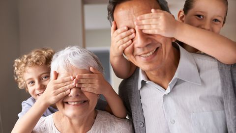 twee kleinkinderen houden handen voor ogen van opa en oma