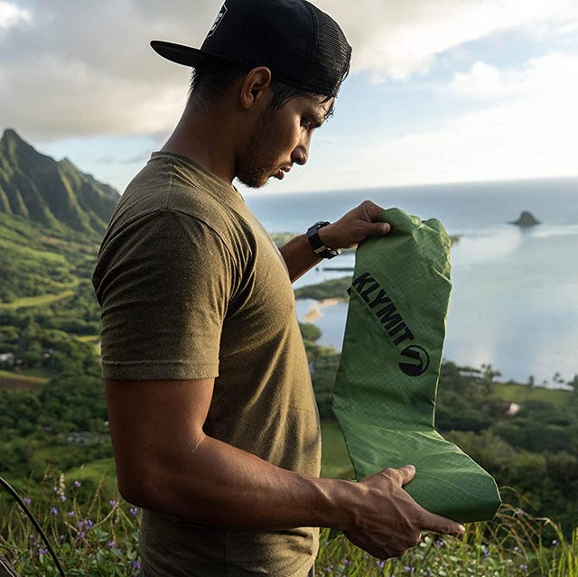 klymit pad a man unfolding a green camping mattress