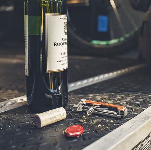 gerber armbar cork a multi tool with an orange handle and corkscrew next to an open bottle of wine
