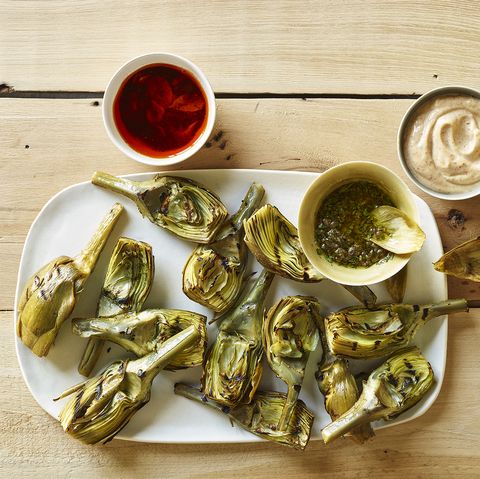 Overhead of grilled artichoke with three sauces