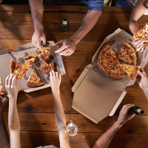 Overhead shot of friends at a table sharing take-away pizzas