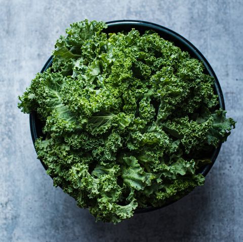 overhead view of a bowl of kale against a gray cement counter