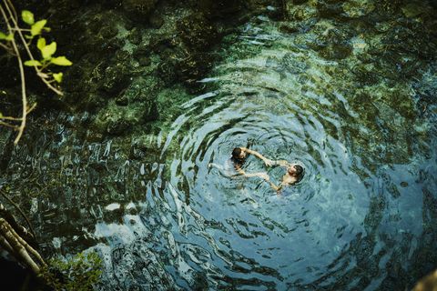 overhead view of couple holding hands while swimming in cenote during vacation