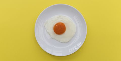 Overhead view of fried egg in plate on yellow background