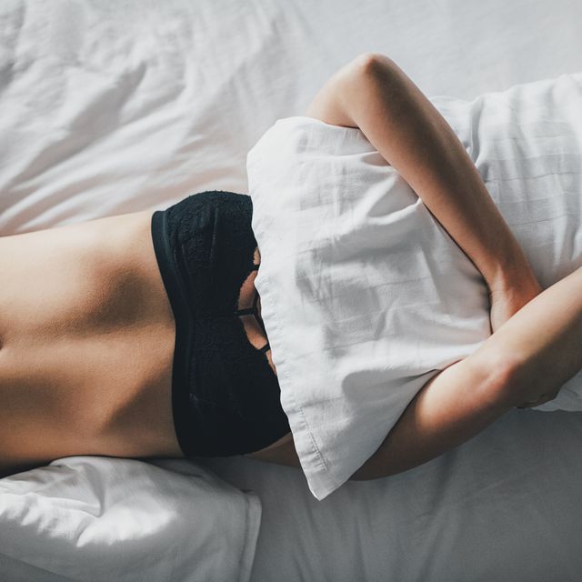 overhead view of sensuous woman covering face with pillow on bed