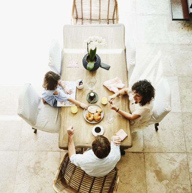 overhead view of smiling wife and husband sharing breakfast with daughter at dining room table