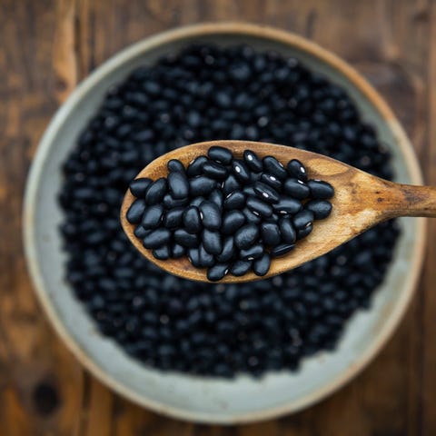 overhead view of spoon and bowl of black bean on wooden table