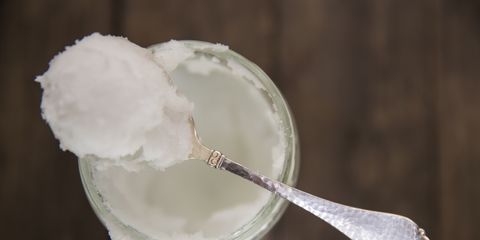 Overhead view of spoonful of cold coconut oil on jar