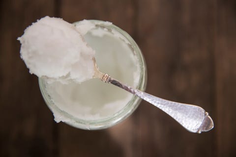 Overhead view of spoonful of cold coconut oil on jar