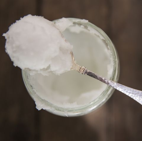 Overhead view of spoonful of cold coconut oil on jar
