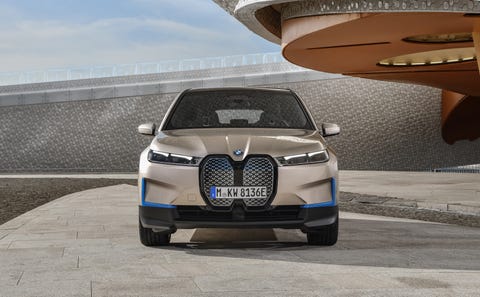bmw ix on a stone driveway in front of a modernist building
