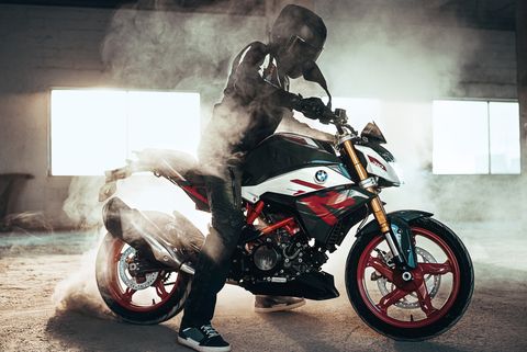 bmw g 310 r motorcycle in a garage with dirt kicked up in the air