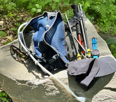 running poles and hydration pack with watch and sunglasses