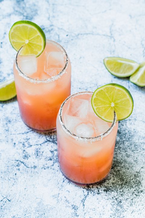 two glasses of paloma cocktails with sugar rims and a lime slice garnish