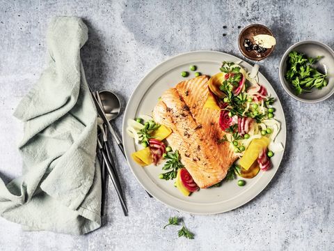 Pan fried salmon with vegetables on gray background