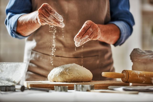 close up view of baker is working homemade bread hands preparing dough on wooden table