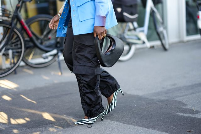 copenhagen, denmark   august 11 a guest wears a blue shiny leather buttoned short skirt, a black shiny leather handbag from coperni, gold rings, black puffy cargo pants, black and white zebra print pattern pointed pumps heels shoes , outside munthe during copenhagen fashion week springsummer 2023, on august 11, 2022 in copenhagen, denmark photo by edward berthelotgetty images