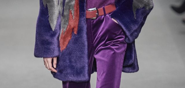 dettaglio pantaloni viola di velluto con cintura rossa e pelliccia colorata
