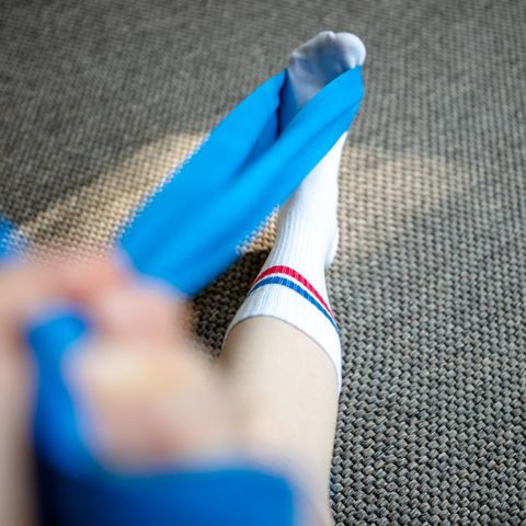 part of a runner woman stretching her leg and foot with a resistance band