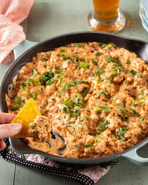party dip recipes sausage dip in skillet with hand holding chip