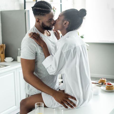 passionate african american couple kissing on kitchen counter at kitchen