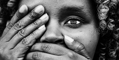 Keniaas meisje in zwart en wit, met haar handen voor haar mond. 