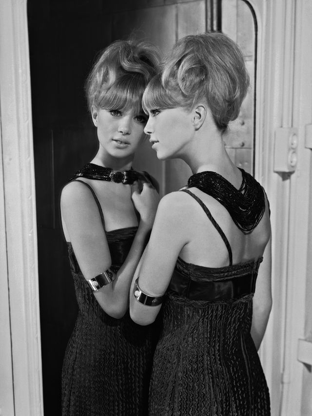 1964  patti boyd in un vestito da sera senza spalline ritratta da dietro mentre si specchia, i capelli sono acconciati su