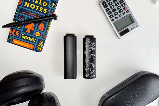 pax plus and pax mini on a table with a notebook, pen, calculator, headphones, and glasses case